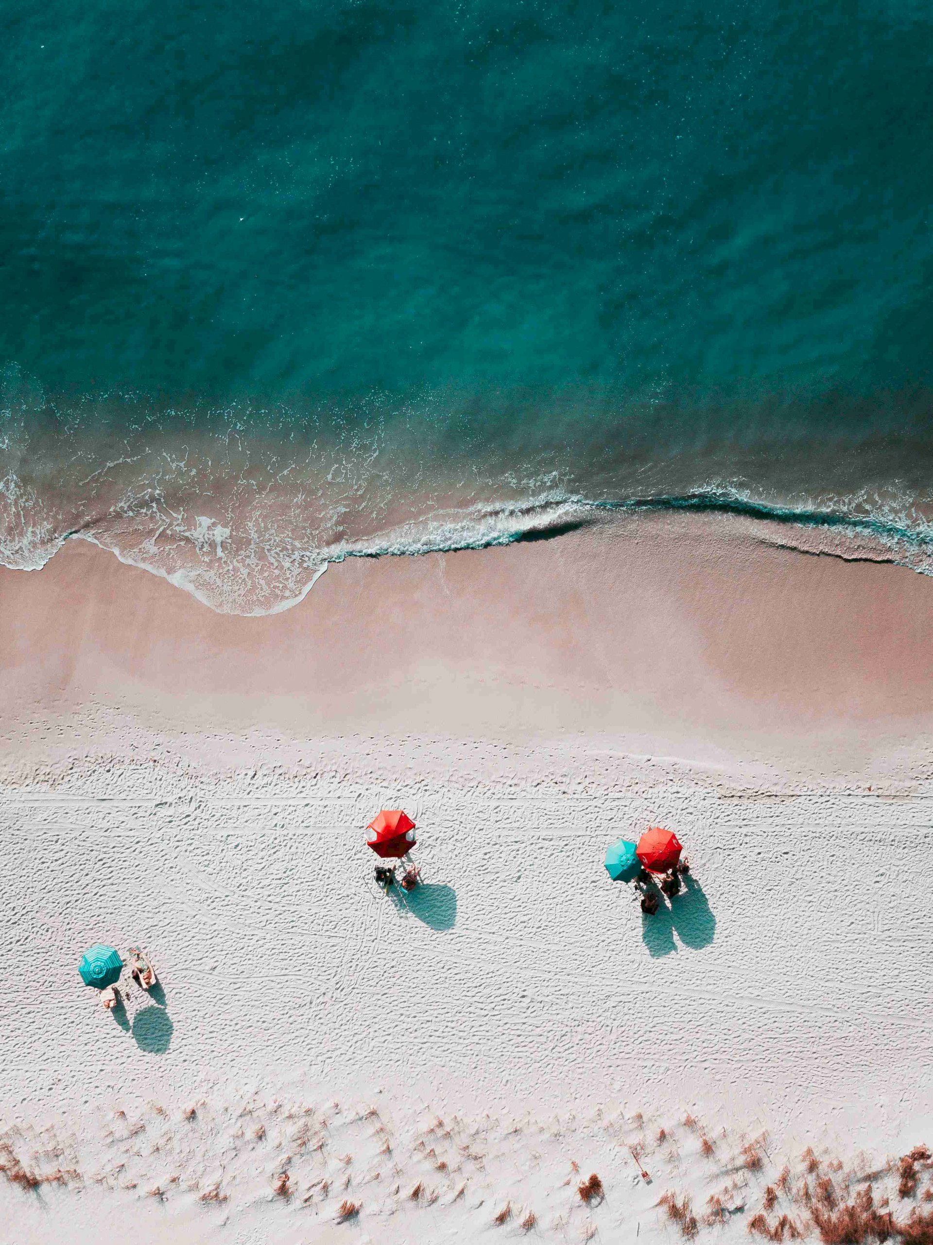 The beach captured from above, ocean and umbrellas. Home-staging a beach house for a better price.